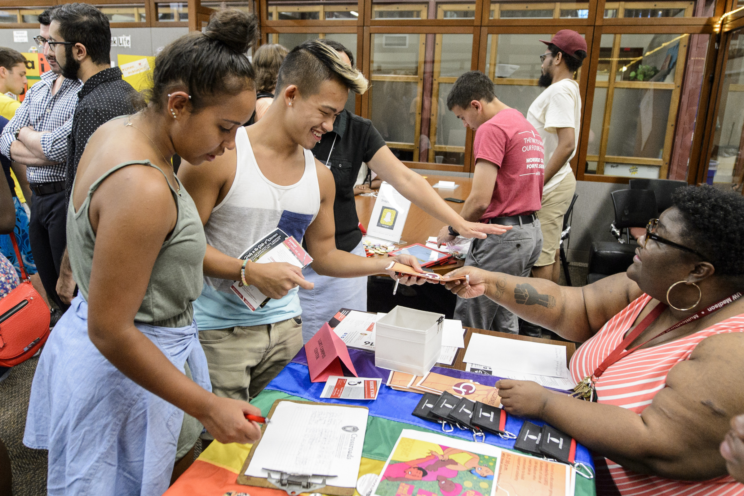 Two undergraduates of color connect with a Black adult seated at the table for the Crossroads organization. They exchange information and literature. (Photo by Bryce Richter / UW-Madison)
